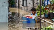 A resident carries belongings while evacuating from his submerged home in the aftermath of Super Typhoon Noru in San Ildefonso, Bulacan province on September 26, 2022. (Photo by Ted ALJIBE / AFP) (Photo by TED ALJIBE/AFP via Getty Images)