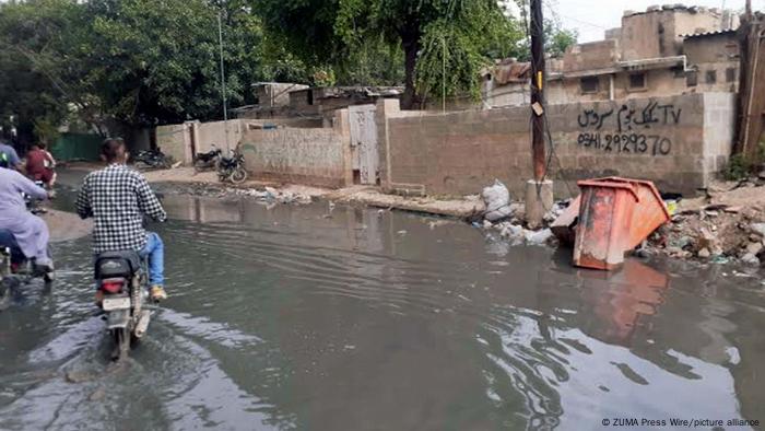 Moped riders drive on flooded road