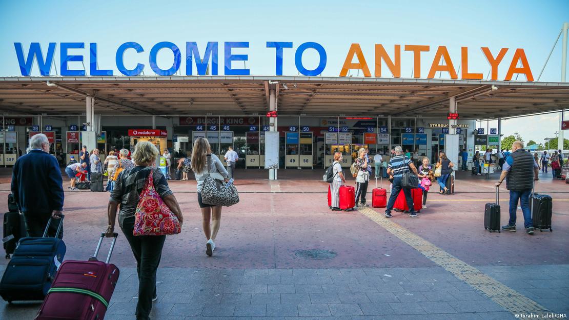 Antalya Havalimanı terminal binasına doğru valizleri ile ilerleyen turistler