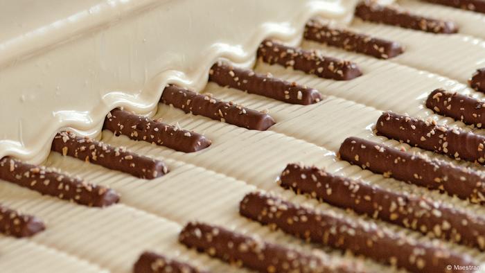 Schokoriegel aus weißer und brauner Schokolade liegen auf einem Blech, weisse Couvertüre wird darüber gegossen Schokoladenfabrik von Maestrani (Schweiz) 