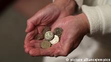 Photo of an elderly woman holding pound coins in her hands