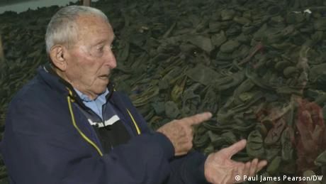 Holocaust survivor Arie Pinsker points to shoes at the Auschwitz memorial