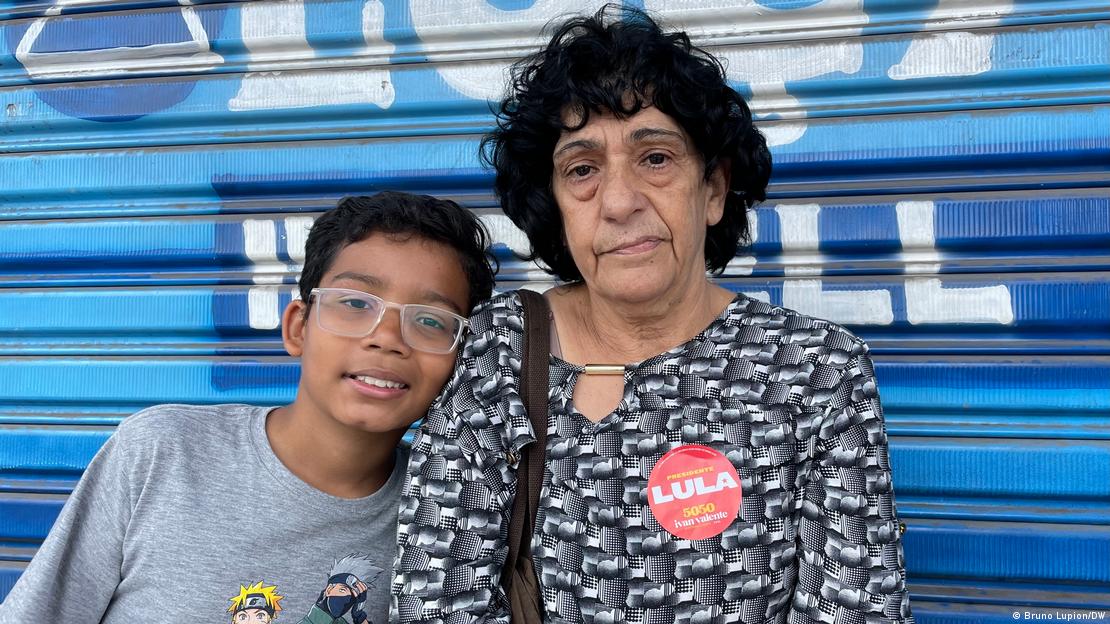 Antônia com um adesivo-pró-Lula ao lado do seu neto, em frente a um portão azul