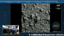 Screenshot from NASA video feed showing two images: The first is a large image of the DART vessel's on-board camera, showing the surface of the asteroid it was about to strike, with the word IMPACT written in the lower right corner. The second is a smaller image of the NASA ground team watching the live feed and cheering the mission's success. September 27, 2022.
