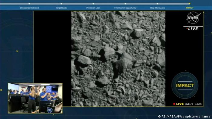 Junto a la imagen grabada por la sonda Dart mientras se acerca al asteroide, la retransmisión de la NASA muestra la sala en la que sus científicos celebran el éxito de la misión.
