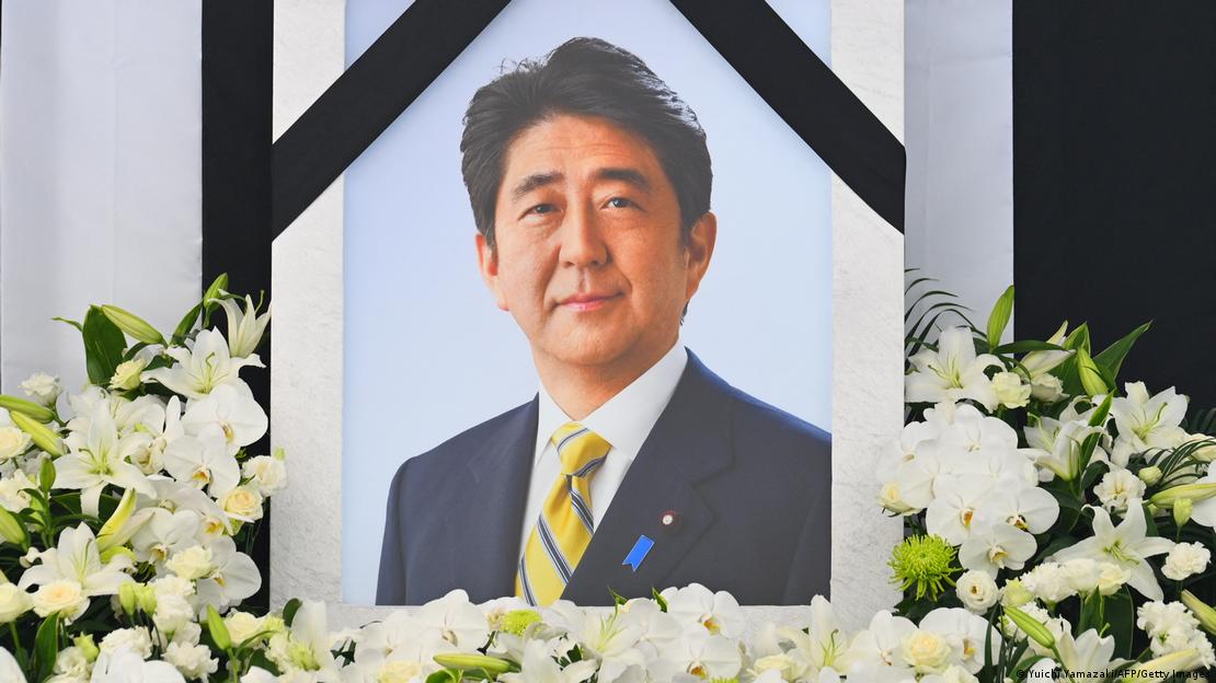Şinzo Abe'nin bir fotoğrafının etrafını süsleyen çiçekler
