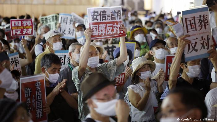 Demonstrators hold signs during a protest against the planned state funeral for slain former Japanese Prime Minister Shinzo Abe in front of Tokyo's JR Shinjuku Station on Sept. 26, 2022, the eve of the ceremony.