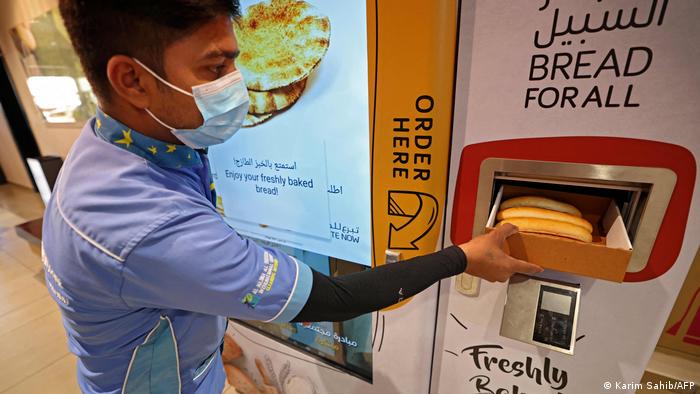 عامل أجنبي يحصل على الخبز مجانا من آلة تقدم الخبز في دبي