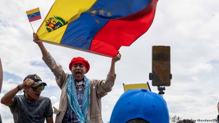 Un hombre celebra en el puente Simón Bolívar ondeando banderas de Colombia y Venezuela.
