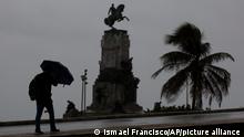 A pedestrian uses an umbrella under the rain during the passing of Hurricane Ian near the Antonio Maceo Monument along the malecon sea wall in Havana, Cuba, early Thursday, Sept. 27, 2022. (AP Photo/Ismael Francisco)