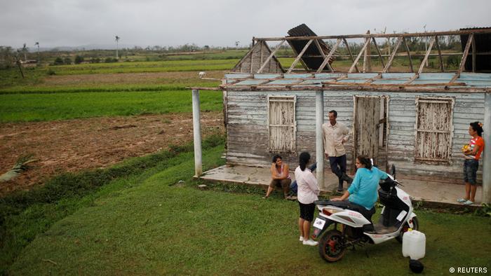 Una familia frente a su casa destruida en Cuba. 