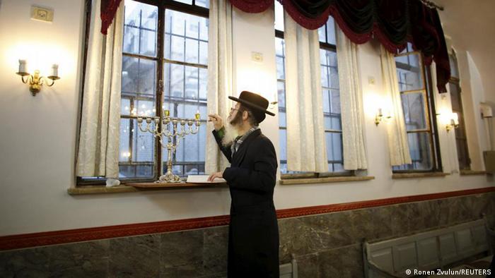 Ein orthodoxer Jude entzündet in einer Synagoge einen Leuchter.