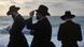 Men dressed in Jewish orthodox fashion pray by the sea Men dressed in Jewish orthodox fashion pray by the sea