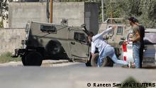 28.09.2022+++ A Palestinian hurls a stone at an Israeli army vehicle during clashes after Israeli forces killed Palestinian gunmen in a raid, in Jenin in the Israeli-occupied West Bank September 28, 2022. REUTERS/Raneen Sawafta 