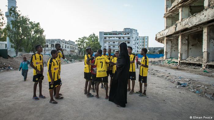 Ilwad Elman dans la rue, à Mogadiscio, entourée de jeunes garçons en tenue de football
