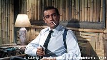Still from 'Dr No': James Bond smoking and holding a gun.
