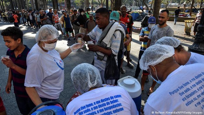 Moradores em situação de rua formam fila para receber comida na Praça da Sé, em São Paulo
