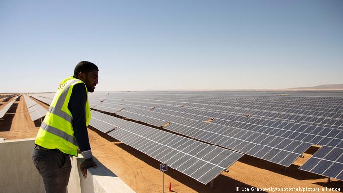 Man stands in front of a large solar park in the Egyptian desert