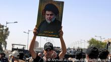 A supporter of Shiite Muslim cleric Moqtada Sadr holds up Sadr's portrait as demonstrators gather in Tahrir Square in the centre of Iraq's capital Baghdad on September 28, 2022 ahead of a parliament session in the nearby high-security Green Zone across the Tigris river. (Photo by Ahmad Al-rubaye / AFP) (Photo by AHMAD AL-RUBAYE/AFP via Getty Images)