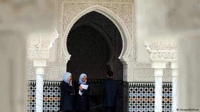 Zwei Frauen stehen vor einem Eingang und neben einer Wand mit typischen Ornamenten am Mechouar-Palast im algerischen Tlemcen