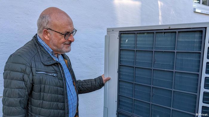 A man looks at an air heat pump that sucks in air from outside