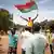 Un manifestant brandit le drapeau du Burkina.