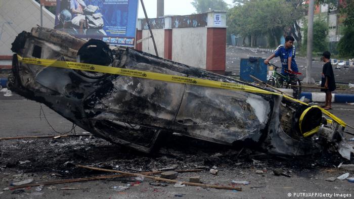Un vehículo tumbado e incendiado en las afueras del estado de Malang, en Java Oriental. Al menos 127 personas murieron en episodios de violencia. (02.10.2022)