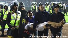Soccer fans carry an injured man following clashes during a soccer match at Kanjuruhan Stadium in Malang, East Java, Indonesia, Saturday, Oct. 1, 2022. Clashes between supporters of two Indonesian soccer teams in East Java province killed over 100 fans and a number of police officers, mostly trampled to death, police said Sunday. (AP Photo/Yudha Prabowo)