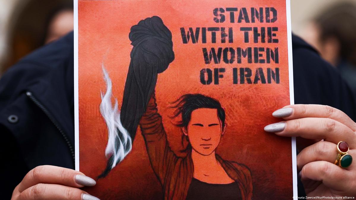 As mãos de uma mulher seguram um cartaz de protesto com os dizeres "esteja com as mulheres do Irã"