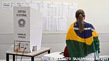 A woman wrapped in a Brazilian flag votes at a polling station during the legislative and presidential election, in Brasilia, Brazil, on October 2, 2022. - Voting began early Sunday in South America's biggest economy, plagued by gaping inequalities and violence, where voters ar expected to choose between far-right incumbent Jair Bolsonaro and leftist front-runner Luiz Inacio Lula da Silva, any of which must garner 50 percent of valid votes, plus one, to win in the first round. (Photo by EVARISTO SA / AFP) (Photo by EVARISTO SA/AFP via Getty Images)