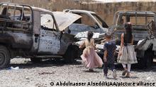 Damaged vehicles and Yemeni kids run after an attack by the Iranian-backed Houthis in Taiz