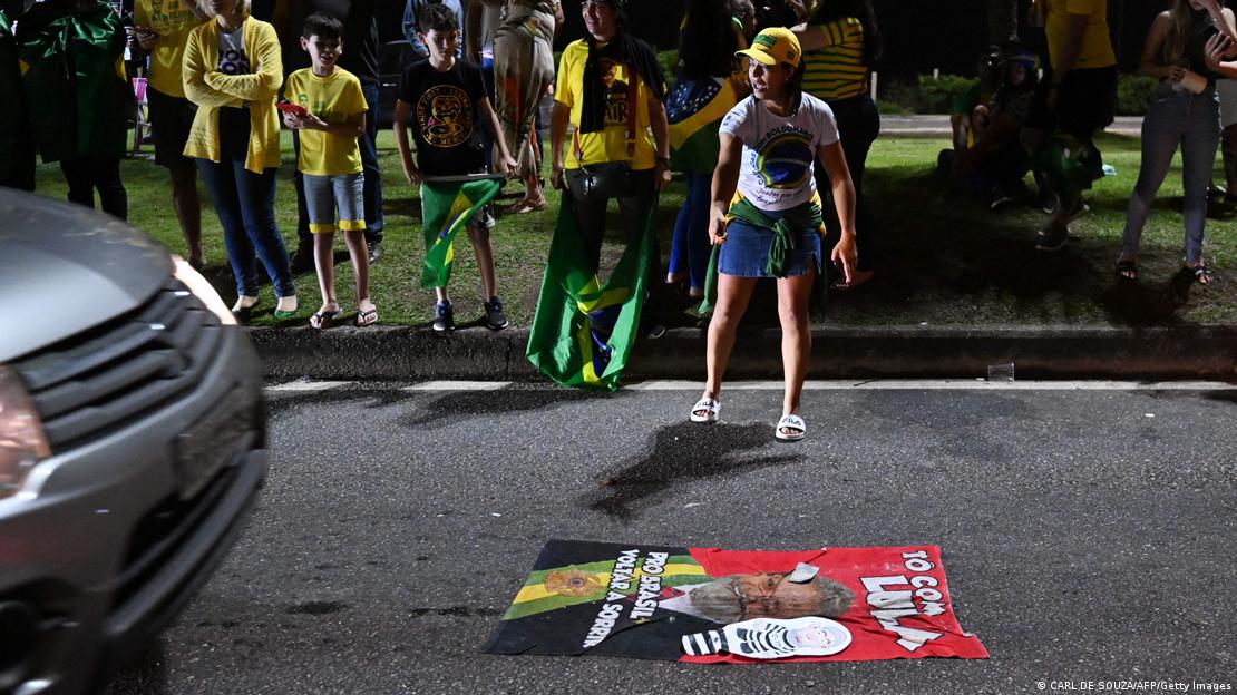 Imagem mostra cartaz do PT com Lula estendido em rua enquanto carro se aproxima para 