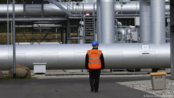Un hombre de pie frente a una parte de la estructura del gasoducto Nord Stream 2.