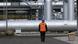 Un hombre de pie frente a una parte de la estructura del gasoducto Nord Stream 2. Un hombre de pie frente a una parte de la estructura del gasoducto Nord Stream 2.