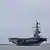 Aircraft carrier with helicopter flying overhead