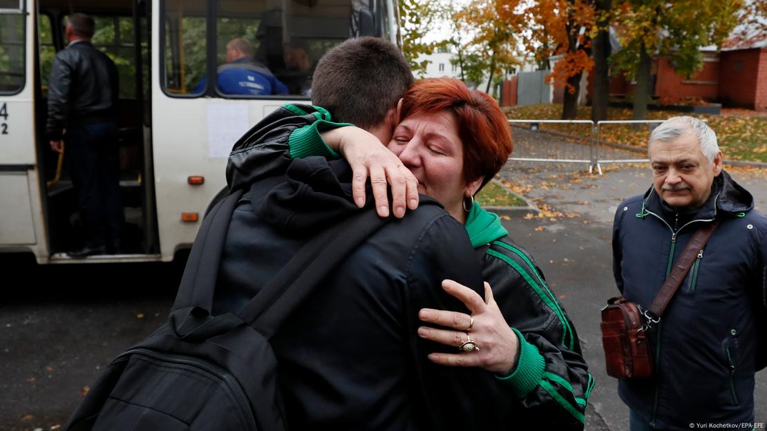 Um jovem russo se despede de seus pais antes de ir para a mobilização militar convocada pelo presidente Vladimir Putin. Ele abraça a mãe, enquanto o pai observa. Ao fundo, o ônibus espera de porta aberta.