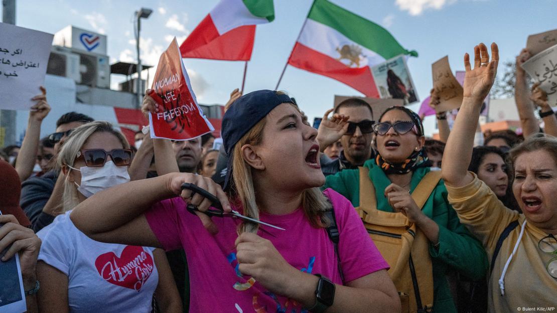 A woman cuts her hair in the middle of a protest.