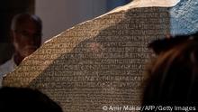 26.07.2022 *** Visitors view the Rosetta Stone at the British Museum in London on July 26, 2022. - The Rosetta Stone a basalt slab dating from 196 BC which bore extracts of a decree written in Ancient Greek, an ancient Egyptian vernacular script called Demotic, and hieroglyphics has been housed in the British Museum since 1802. The three scripts finally provided the code for unlocking the mysteries of hieroglyphs which had bedevilled historians for centuries. But the stone is on display with an explanation that it was captured in Egypt by the British Army in 1801 from Napoleonic forces and was presented by King George III to the museum. - RESTRICTED TO EDITORIAL USE - NO MARKETING NO ADVERTISING CAMPAIGNS (Photo by Amir MAKAR / AFP) / RESTRICTED TO EDITORIAL USE - NO MARKETING NO ADVERTISING CAMPAIGNS (Photo by AMIR MAKAR/AFP via Getty Images)