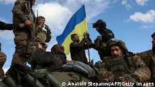 TOPSHOT - Ukrainian soldiers adjust a national flag atop a personnel armoured carrier on a road near Lyman, Donetsk region on October 4, 2022, amid the Russian invasion of Ukraine. - Ukraine's President Volodymyr Zelensky said on October 2, 2022 that Lyman, a key town located in one of four Ukrainian regions annexed by Russia, had been cleared of Moscow's troops. (Photo by Anatolii Stepanov / AFP) (Photo by ANATOLII STEPANOV/AFP via Getty Images)