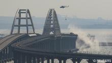 A helicopter drops water to extinguish fuel tanks ablaze on the Kerch bridge in the Kerch Strait, Crimea, October 8, 2022. REUTERS/Stringer 