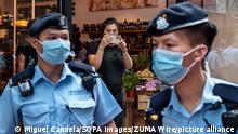 July 1, 2021, Hong Kong, China: A shop worker takes a picture of police officers as they stand guarded in Hong Kong on July 1, 2021. Hong Kong celebrates its 24th anniversary of the handover to China and the 100th anniversary of the founding of the Communist Party of China. (Credit Image: © Miguel Candela/SOPA Images via ZUMA Wire