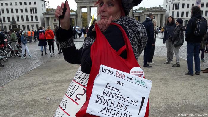 Demonstrantin Heidi Bethke vor dem Brandenburger Tor in Berlin; auf einem Plakat steht: Weder rechts noch links, aber gegen Wahlbetrug und Bruch des Amtseids