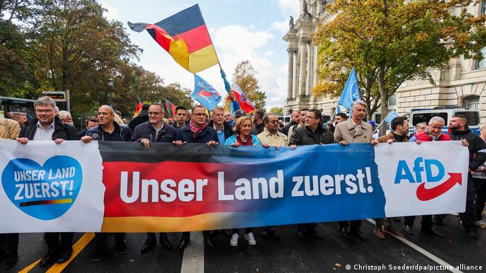 Spitzenpersonal der Alternative für Deutschland (AfD) demonstriert mit einem quer über die ganze Straße reichenden Transparent unter dem Motto Unser Land zuerst! durch Berlin; im Hintergrund das Reichstagsgebäude. 