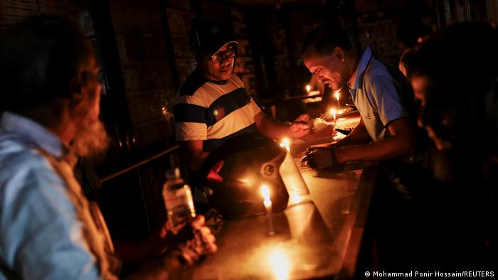 A pharmaceutical shop uses candle lights to serve customers during a countrywide blackout in Dhaka, Bangladesh