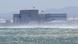 A person windsurfing passes across waves in front of the South African power utility Eskom's Koeberg Nuclear Power Station at Mekbosstrand, in Cape Town, South Africa. A person windsurfing passes across waves in front of the South African power utility Eskom's Koeberg Nuclear Power Station at Mekbosstrand, in Cape Town, South Africa.