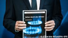 epa10234027 German Chancellor Olaf Scholz poses with a report reading 'safe through the winter' during the handover of the proposal of the independent commission on natural gas and heat to the German Government at the Chancellery in Berlin, Germany, 10 October 2022. The commission consulted on how to relieve citizens, dealing with rising energy costs. EPA-EFE/CLEMENS BILAN