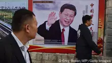 TOPSHOT - People walk past a poster featuring Chinese President Xi Jinping with a slogan reading Chinese Dream, People's Dream beside a road in Beijing on October 16, 2017. As Chinese leader Xi Jinping prepares to embark on a second five-year term this week, the impulsive leaders of North Korea and the United States could spoil his party. / AFP PHOTO / GREG BAKER (Photo credit should read GREG BAKER/AFP via Getty Images)