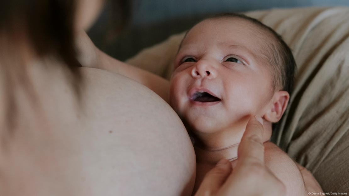 A baby being breastfed smiles at his mother