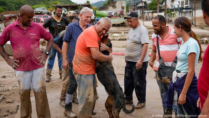 Un hombre abraza a su perro, que fue rescatado del barro por vecinos.