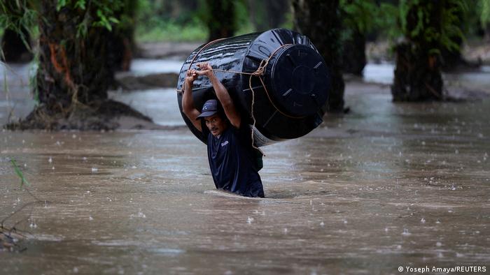 Un hombre lleva un tonel de agua vacío a través de una zona inundada en el municipio de Progreso, Honduras. 
